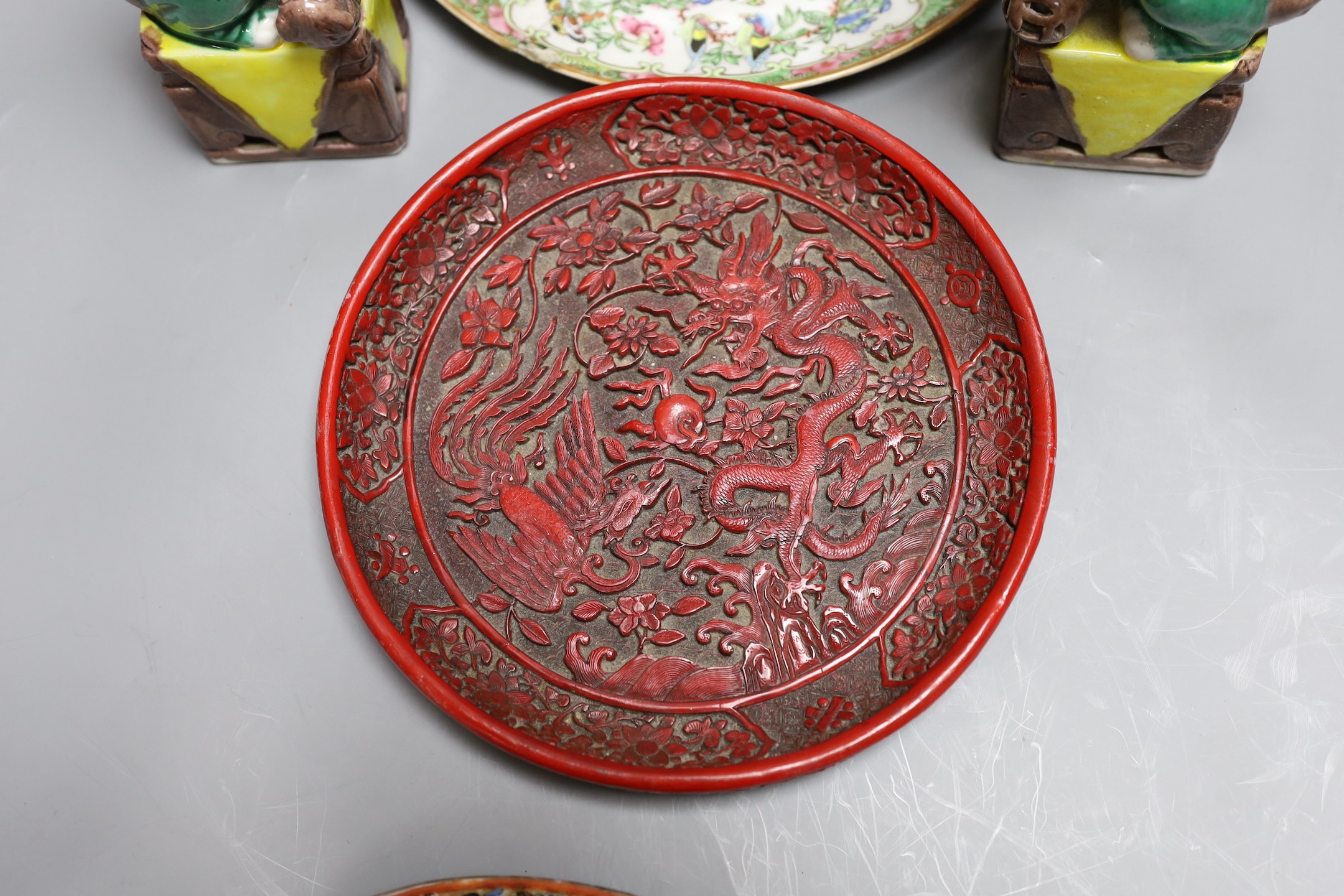 A Cantonese famille rose plate and teapot with cover, a pair of Chinese seated dogs, and a tureen with cover and oval dish, And a Chinese faux lacquer dragon and Phoenix dish, teapot 18 cms high